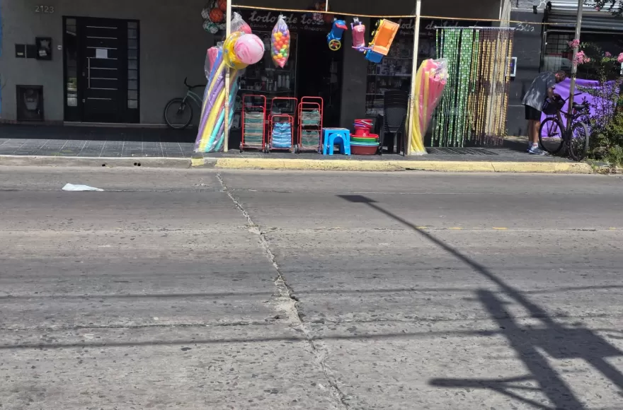 Un bazar exhibe mercadería en la vereda, como pelotas, artículos de plástico, productos de temporada, ocupando el frente como estrategia para atraer clientes.