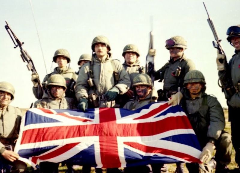 Soldados argentinos con bandera británica como trofeo de guerra.