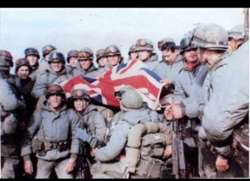 Soldados argentinos con bandera británica como trofeo de guerra.