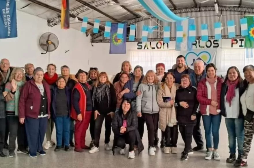 Muchas vecinas y vecinos se acercan a compartir una comida.